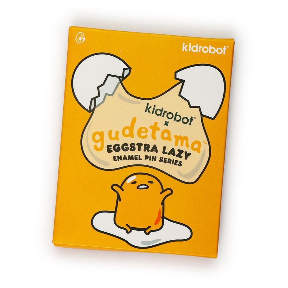 Gudetama Eggstra Lazy enamel pin from Kidrobot x Sanrio featuring the relaxed egg character, displayed in a blind box packaging.